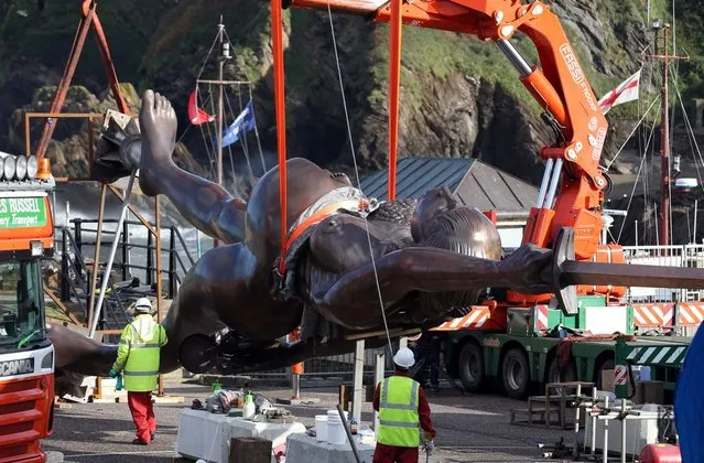 Contractors move Damien Hirst's bronze sculpture of a pregnant woman into position on the harbour wall on October 16, 2012 in Ilfracombe, England. The bronze-clad, sword-wielding 65ft (20m) statue, named Verity, has been controversially given to the seaside town by the artist, on a 20-year loan and was erected by crane on the pier.  (Photo by Matt Cardy)