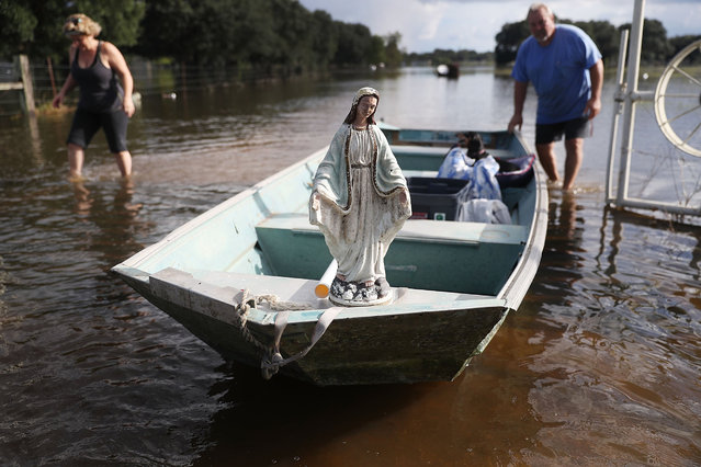 Leigh Babin and her husband TJ Babin bring items they recovered from their flooded home to shore along with a statue of the Virgin Mary that they found in the flood waters on August 17, 2016 in Sorrento, Louisiana. Starting last week Louisiana was overwhelmed with flood water causing at least seven deaths and thousands of homes damaged by the flood waters. (Photo by Joe Raedle/Getty Images)