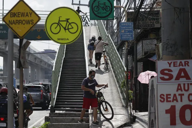 Residents push their bicycles up a bridge as public transportation still remains unavailable during the community quarantine on the outskirts of Manila, Philippines on Monday, May 18, 2020. Crowds and vehicular traffic returned to shopping malls in the Philippine capital after a two-month coronavirus lockdown was partially relaxed over the weekend, prompting police to warn of arrests and store closures. (Photo by Aaron Favila/AP Photo)