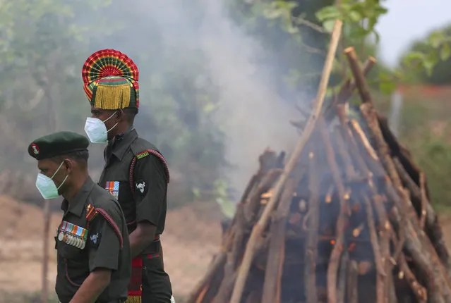 Indian army officers wearing masks as a precaution against the coronavirus walk past the funeral pyre of their colleague Colonel B. Santosh Babu, at Suryapet, about 140 kilometers (87.5 miles) from Hyderabad, India, Thursday, June 18, 2020. Babu was among the twenty Indian troops who were killed in the clash Monday night that was the deadliest conflict between the sides in 45 years. India on Thursday cautioned China against making "exaggerated and untenable claims" to the Galvan Valley area even as both nations tried to end a standoff in the high Himalayan region where their armies engaged in a deadly clash. (Photo by Mahesh Kumar A./AP Photo)