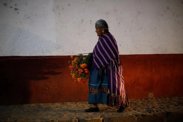 A women carries Cempasuchil Marigolds during the annual Day of the Dead celebration in Santa Fe de La Laguna, Michoacan state, Mexico on November 1, 2022. (Photo by Raquel Cunha/Reuters)
