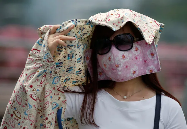 A woman wearing a face mask shields her face from the sun as haze shrouds Singapore August 26, 2016. (Photo by Edgar Su/Reuters)
