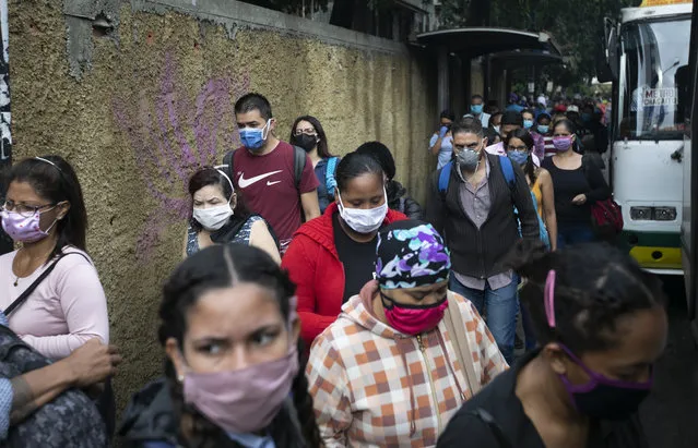 Pedestrians and commuters wearing face masks amid the new coronavirus pandemic crowd a sidewalk near a bus stop in Caracas, Venezuela, Monday, June 1, 2020. After two and a half months of COVID-19 related quarantine, some industries are allowed to reactivate under a scheme of five days' work and 10 days rest. (Photo by Ariana Cubillos/AP Photo)