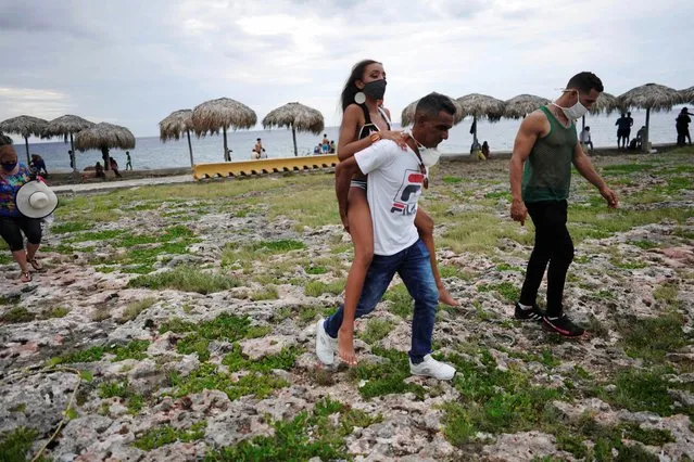Naomi Ramos is carried by her father during a photo session for her quinceanera (coming of age of 15-year-olds) celebration amid coronavirus disease (COVID-19) spread concerns, in Havana, Cuba, July 19, 2020. (Photo by Alexandre Meneghini/Reuters)