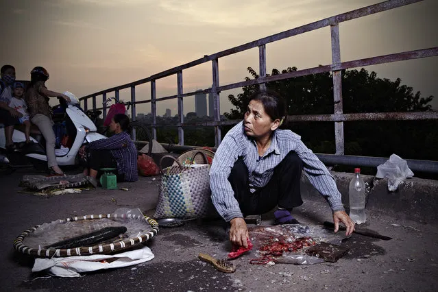 “Catch of the Day”. The sun was setting as a woman on Long Bien bridge hastily gutted and sold fresh fish to commuters on their way home. Photo location: Hanoi, Vietnam. (Photo and caption by Alexander Savvas/National Geographic Photo Contest)