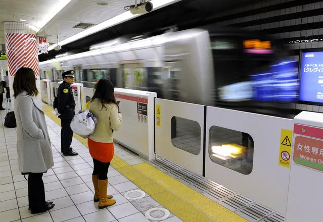 Passengers wait behind a platform-edge barrier at Kitashinchi Station on the Tozai Line in the city of Osaka in March 2011. (Photo by Kyodo News)
