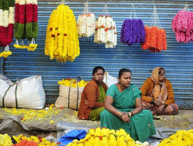 Vendors selling flower garlands on a pavement wait for customers outside a flower market in the southern Indian city of Bangalore October 22, 2014. (Photo by Abhishek N. Chinnappa/Reuters)