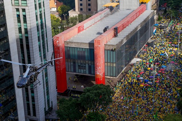 A Civil Police helicopter flies over a rally in support of former Brazilian President Jair Bolsonaro in Sao Paulo, Brazil, on February 25, 2024, to reject claims he plotted a coup with allies to remain in power after his failed 2022 reelection bid. Investigators say the far-right ex-army captain led a plot to falsely discredit the Brazilian election system and prevent the winner of the vote, leftist President Luiz Inacio Lula da Silva, from taking power. A week after Lula took office on January 1, 2023, thousands of Bolsonaro supporters stormed the presidential palace, Congress and Supreme Court, urging the military to intervene to overturn what they called a stolen election. (Photo by Miguel Schincariol/AFP Photo)