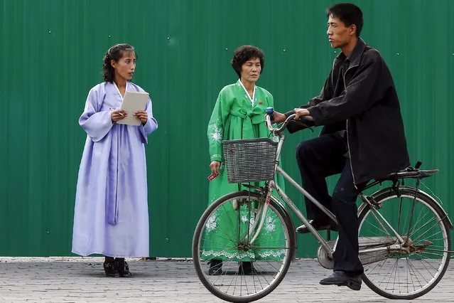 A man rides a bicycle past women wearing traditional clothes in downtown Pyongyang, North Korea October 8, 2015. (Photo by Damir Sagolj/Reuters)