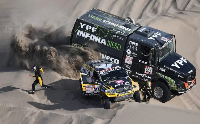 Renault' s Portuguese driver Carlos Souza (R) and French co- driver Pascal Maimon run for safety as Iveco' s Argentine truck driver Federico Villagra, co- driver Ricardo Torlaschi and mechanic Adrian Yacopini ride past during the 2018 Dakar Rally Stage 5 between San Juan De Marcona and Arequipa in Peru, on January 10, 2018. Sebastien Loeb was forced to pull out of the Dakar Rally after a back injury suffered by his co- driver in a disastrous fifth stage won by defending champion Stephane Peterhansel. (Photo by Franck Fife/AFP Photo)