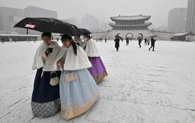Visitors wearing traditional hanbok dress walk through Gyeongbokgung palace during snowfall in central Seoul on December 15, 2022. (Photo by Jung Yeon-je/AFP Photo)