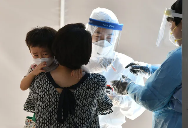 A medical staff (C) takes test samples for the COVID-19 coronavirus from a boy (L) at a coronavirus testing station in Seoul on August 18, 2020. South Korea on August 18 ordered nightclubs, museums and buffet restaurants closed and banned large-scale gatherings in and around the capital as a burst of new coronavirus cases sparked fears of a major second wave. (Photo by Jung Yeon-je/AFP Photo)