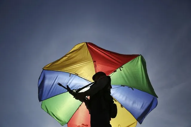 A policeman stands guard under a colourful umbrella along the road leading to the ASEAN summit venue as security in tightened in Naypyitaw November 10, 2014. Leaders from ASEAN, East Asian and other countries will gather for the ASEAN summit this week in Myanmar's capital, Naypyitaw. United States President Barak Obama is scheduled to attend. (Photo by Damir Sagolj/Reuters)