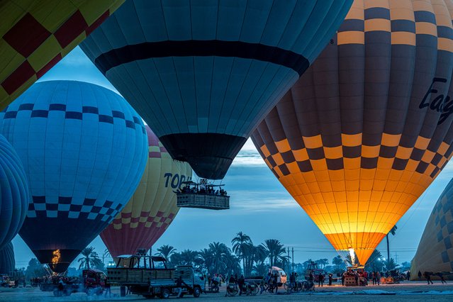 Tourists are helped to get into the basket of a hot air balloon before flying above the west bank of the Nile river in Egypt's southern city of Luxor early on January 9, 2025. (Photo by Khaled Desouki/AFP Photo)