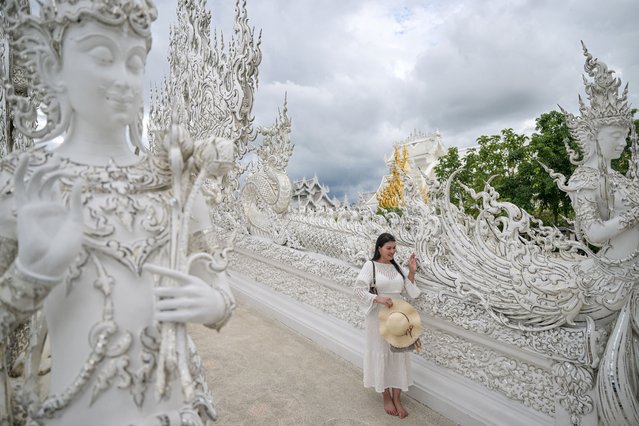 This picture taken on May 24, 2025, shows a tourist posing for photographs at the Wat Rong Khun Buddhist temple, popularly known as “White Temple”, in northern Thailand's Chiang Rai province. (Photo by Manan Vatsyayana/AFP Photo)