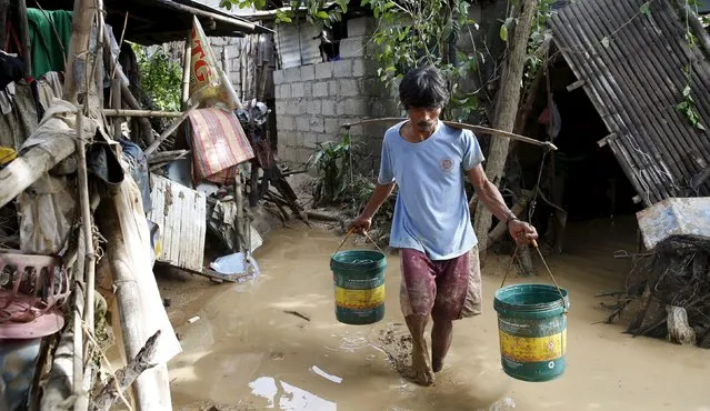 A resident carries water containers as he wades through muddy floodwaters in Cabanatuan city, Nueva Ecija in northern Philippines October 20, 2015, after the province was hit by Typhoon Koppu. (Photo by Erik De Castro/Reuters)