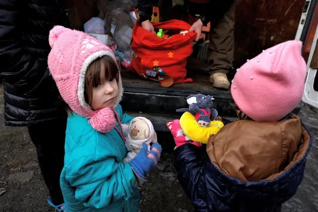 Oleksandra, 3, receives a Christmas gift from humanitarian aid organisation UA Future, who are delivering gifts to children living in underground shelters ahead of Orthodox Christmas, as Russia's attack on Ukraine continues, in Bakhmut, Ukraine on January 4, 2023. (Photo by Clodagh Kilcoyne/Reuters)