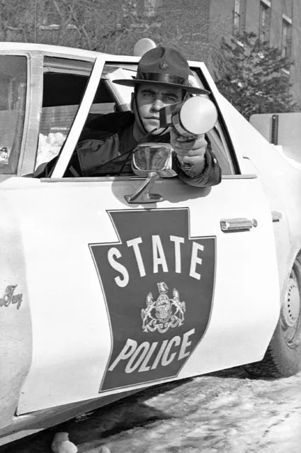 Pennsylvania State Police Trooper A. J. Probst leans out of window of his patrol car displaying the new portable radar unit in Harrisburg, Pa., on January 25, 1978 the state police will use starting February 1. The new units are expected to be more effective than previous models. The radar gun can operate in both directions and records speed on back of unit which is hand held. (Photo by Paul Vathis/AP Photo)