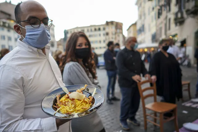 A man holds a plate of “Carbonara” spaghetti as restaurant owners protest against the government restriction measures to curb the spread of COVID-19, closing restaurants at night, in Rome, Wednesday, October 28, 2020. For at least the next month cafes and restaurants must shut down in early evenings, under a decree signed on Sunday by Italian Premier Giuseppe Conte. (Photo by Andrew Medichini/AP Photo)