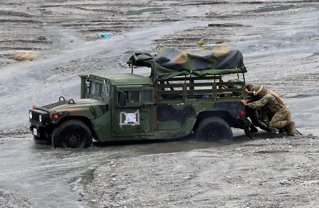 U.S.-Philippines military push a military vehicle stuck on a muddy area during the annual  Philippines-US live fire amphibious landing exercise (PHIBLEX) at Crow Valley in Capas, Tarlac province, north of Manila, Philippines October 10, 2016. (Photo by Romeo Ranoco/Reuters)