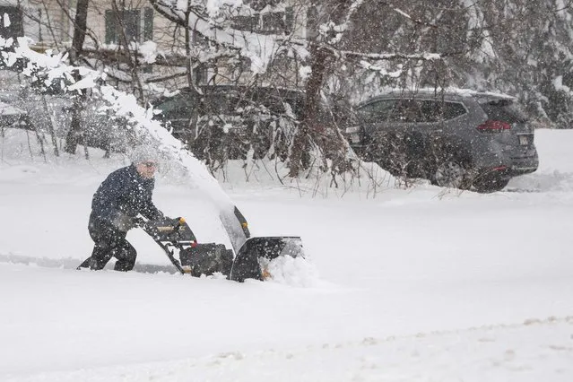 A person tries to use a snowblower to clear snow from their driveway, over a foot deep, during a nor’easter in Rutland, Massachusetts on March 14, 2023. A major Nor'easter is expected to bring heavy snow and strong winds to the East Coast on Wednesday, forecasters say. (Photo by Joseph Prezioso/AFP Photo)