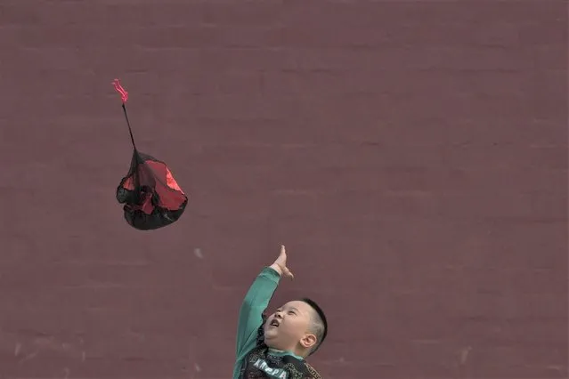 A child plays with a parachute toy at a park in Beijing, Sunday, March 19, 2023. (Photo by Andy Wong/AP Photo)
