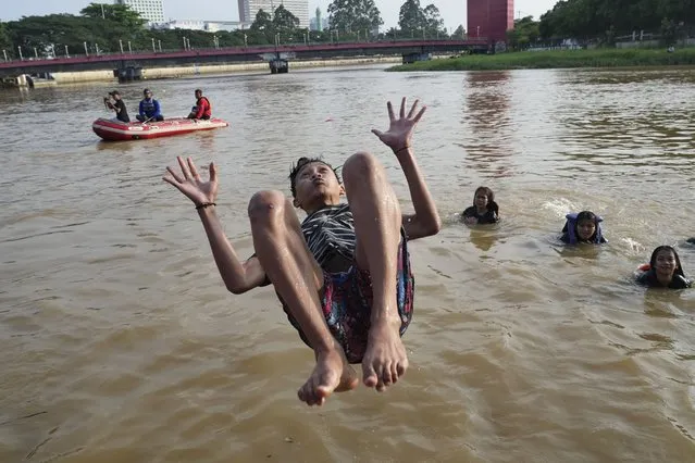 A man jumps into the Cisadane River, ahead the holy fasting month of Ramadan in Tangerang, Indonesia, Tuesday, March 21, 2023. Muslims followed local tradition to wash in the river to symbolically cleanse their soul prior to entering the holiest month in Islamic calendar. (Photo by Tatan Syuflana/AP Photo)