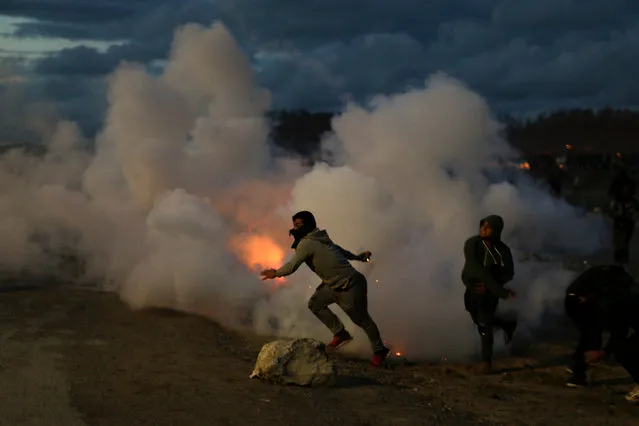 Demonstrators throw back tear gas canisters to French riot police officers during clashes in a makeshift migrant camp known as “the jungle” near Calais, northern France, on Saturday, October 22, 2016. French authorities say the closure of the slum-like camp in Calais will start on Monday and will last approximatively a week in what they describe as a “humanitarian” operation. (Photo by Emilio Morenatti/AP Photo)