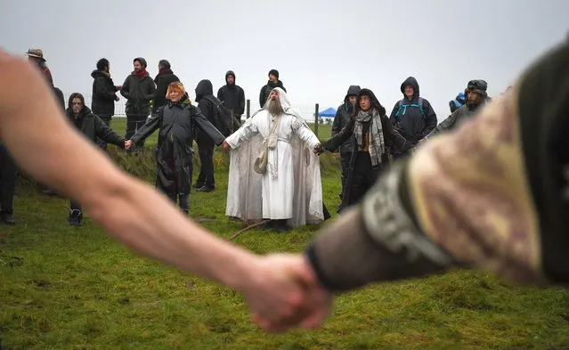 Participants take part in a ceremony at the closed Stonehenge on December 21, 2020 in Amesbury, United Kingdom. English Heritage, which manages the site, said “Owing to the pandemic, and in the interests of public health, there will be no Winter Solstice gathering at Stonehenge this year. We look forward to welcoming people back for solstice next year”. (Photo by Finnbarr Webster/Getty Images)
