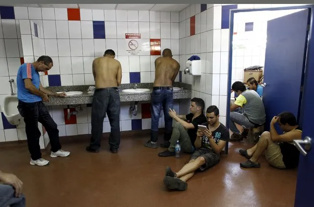 Cuban migrants use their cell phones in a bathroom at the border between Costa Rica and Nicaragua in Penas Blancas, November 18, 2015. Costa Rica proposed a "humanitarian corridor" for Cuban migrants transiting Central America on their way to the United States. Some 2,000 Cuban migrants are at the northern border with Nicaragua, and some 300 Cubans are expected to arrive at Costa Rica's southern border with Panama every day. (Photo by Juan Carlos Ulate/Reuters)