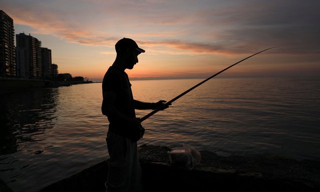 A fisherman dangles his line to catch fish during sunset at Beirut's seaside Corniche, Lebanon on May 4, 2025. (Photo by Orhan Qereman/Reuters)