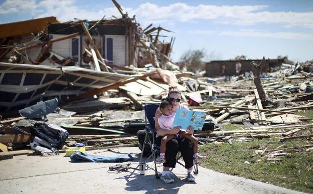 Sarah Dick reads a Doctor Seuss book to her three-year-old daughter Jadyn at the driveway of her tornado-destroyed house in Oklahoma City, Oklahoma May 22, 2013. Rescue workers with sniffer dogs picked through the ruins on Wednesday to ensure no survivors remained buried after a deadly tornado left thousands homeless and trying to salvage what was left of their belongings. (Photo by Rick Wilking/Reuters)