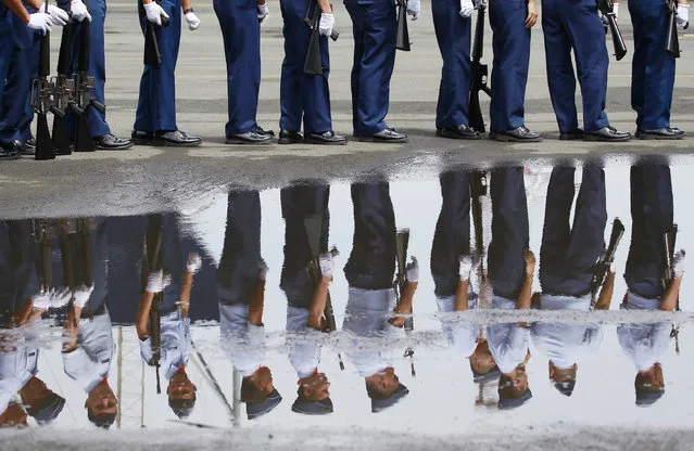 Members of the Philippine Coast Guard are reflected in a puddle of water after participating in handover ceremonies of the BRP Tubbataha at the Philippine Coast Guard headquarters in Manila, Philippines on Thursday, August 18, 2016. The Philippine Coast Guard ship is the first of ten multi-role response vessels to be built by the Japan Marine United Corporation, Yokohama shipyard as part of the Maritime Safety Capability Improvement Project with Japan. (Photo by Aaron Favila/AP Photo)