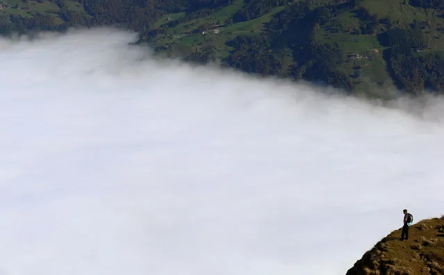 A hiker stands above the fog near the peak of Mount Rigi, Switzerland at 1,797 m (5,896 ft) above sea level October 16, 2016. (Photo by Arnd Wiegmann/Reuters)