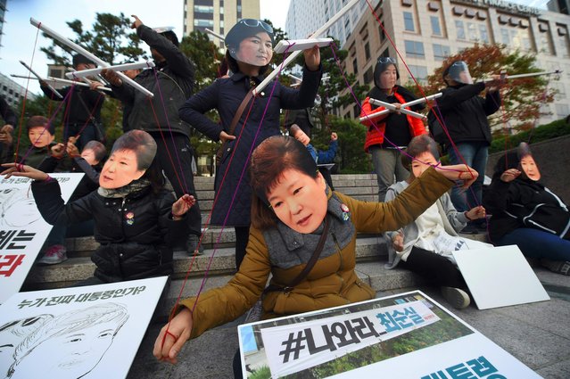 Protesters wearing masks of South Korean President Park Geun-Hye (front) and her confidante Choi Soon-Sil (back) perform before a candle-lit rally in central Seoul on October 29, 2016 to denounce Park over a high-profile corruption and influence-peddling scandal involving her close friend. South Korean prosecutors on October 29 raided the homes and offices of senior advisers to President Park Geun-Hye, as she struggled with a corruption and influence-peddling scandal involving a close family friend. (Photo by Jung Yeon-Je/AFP Photo)