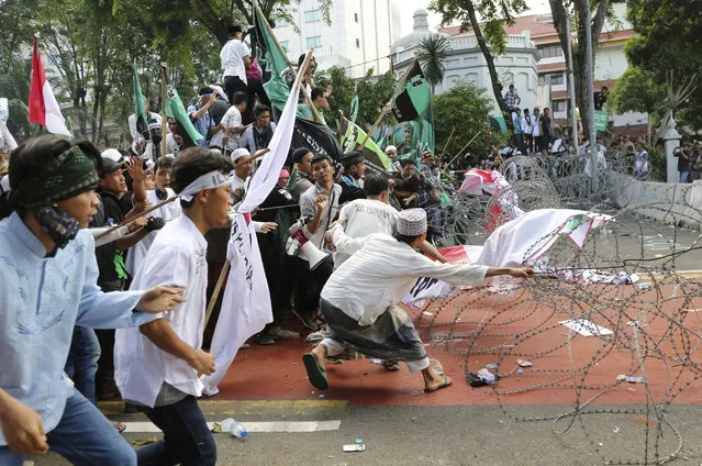 Muslim protesters pull razor wire blocking a road that leads to the presidential palace during a rally against Jakarta Governor Basuki Tjahaja Purnama in Jakarta, Indonesia, Friday, November 4, 2016. (Photo by Tatan Syuflana/AP Photo)