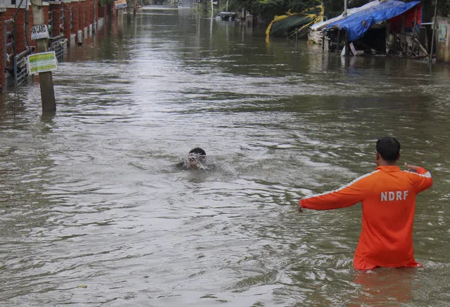 A National Disaster Response Force person, right, arrives to rescue a boy who fell while wading through flood waters in Chennai, India, Thursday, December 3, 2015. The heaviest rainfall in more than 100 years has devastated swathes of the southern Indian state of Tamil Nadu, with thousands forced to leave their submerged homes and schools, offices and a regional airport shut for a second day Thursday. (Photo by AP Photo)