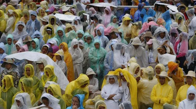 Nuns wear raincoats as thousands of people gather at Rizal Park to attend a mass by Pope Francis in Manila January 18, 2015. Huge crowds converged on the Manila park on Sunday to see Pope Francis wrap up his Asian trip with an outdoor Mass expected to draw one of the largest crowds in Philippine history. (Photo by Erik De Castro/Reuters)