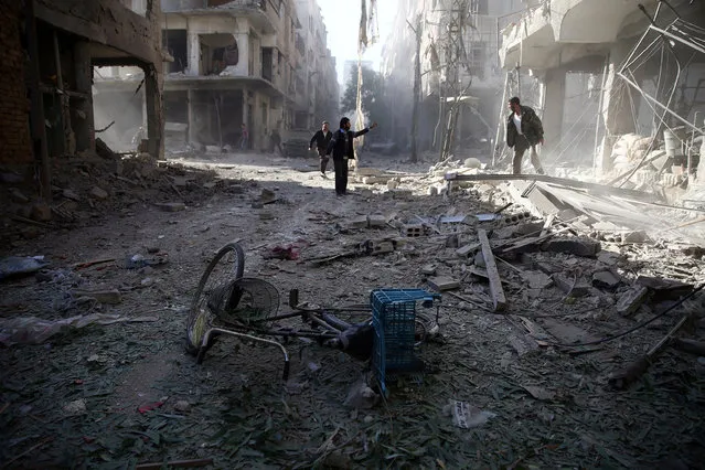 Men inspect a damaged site after an airstrike in the besieged rebel-held town of Douma, eastern Ghouta in Damascus, Syria November 2, 2016. (Photo by Bassam Khabieh/Reuters)