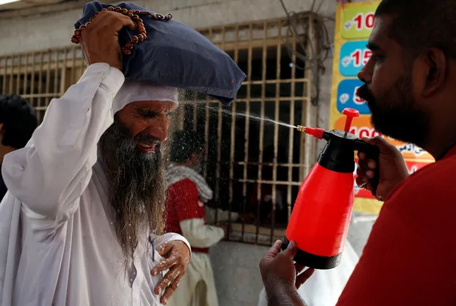 A man reacts as he receives a spray of cold water, to avoid the intense heatwave, at a stall, setup by a social welfare organization in Karachi, Pakistan on May 22, 2018. (Photo by Akhtar Soomro/Reuters)