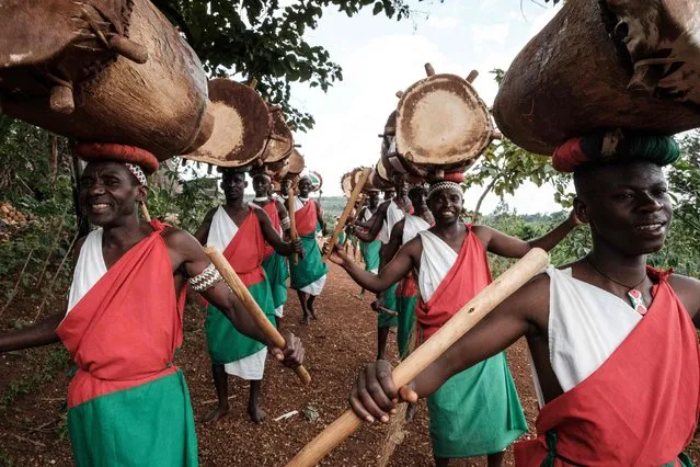 Elite drummers start performing for tourists at Gishora Drum Sanctuary in Gishora, Burundi, on March 12, 2022. Against a backdrop of rolling green hills, a troupe of barefoot musicians wearing the national colours of Burundi strike huge wooden drums with tremendous force, precision, and unabashed enjoyment. Twirling and singing, a stick in each hand, the performers and their royal drums are the custodians of a centuries-old ritual recognised by UNESCO, and one jealously guarded by the Burundian state. (Photo by Yasuyoshi Chiba/AFP Photo)