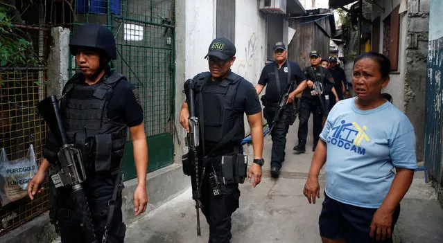 Police from the SWAT team walk past a resident during an anti-drugs operation in Mandaluyong, metro Manila in the Philippines, November 12, 2016. (Photo by Erik De Castro/Reuters)