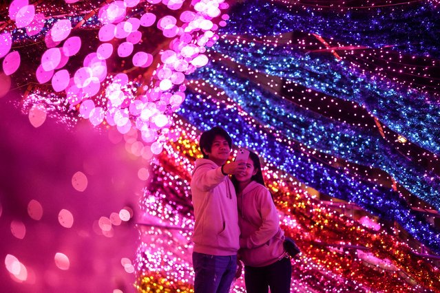 A couple takes a selfie at a Christmas light tunnel during the 2024 New Taipei Christmasland on Christmas eve in New Taipei City on December 24, 2024. (Photo by I-Hwa Cheng/AFP Photo)