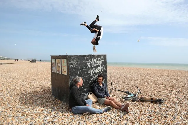 Parkour athlete Lynn Jung trains in Brighton while people are seen relaxing on the beach, following the outbreak of the coronavirus disease (COVID-19), Brighton, Britain on May 22, 2020. (Photo by Peter Cziborra/Reuters)