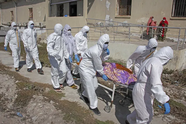 Medical workers in protective suits remove the body of Fatima Abdi, 51, who died from COVID-19 according to her daughter, from a ward for coronavirus patients at the Martini hospital in Mogadishu, Somalia Wednesday, February 24, 2021. (Photo by Farah Abdi Warsameh/AP Photo)