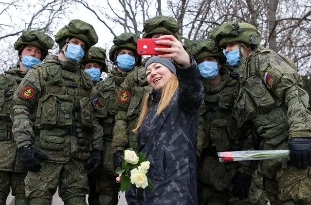 A woman takes a selfie with Russian servicemen during an International Women's Day celebration in Sevastopol, Crimea on March 8, 2021. (Photo by Alexey Pavlishak/Reuters)