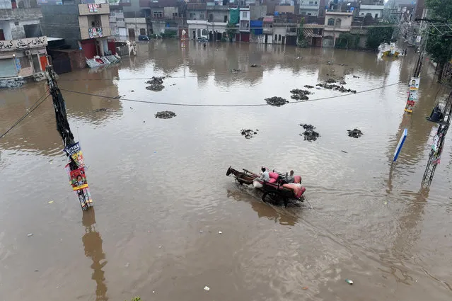 A Pakistani man rides on his horse cart through a flooded square after heavy rains in Lahore on July 3, 2018. (Photo by Arif Ali/AFP Photo)