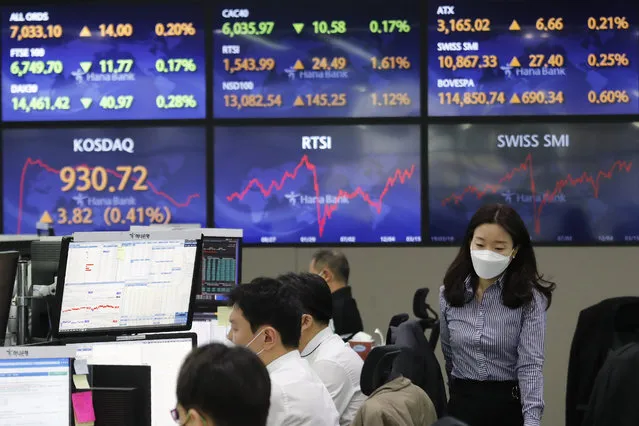 A currency trader passes by screens showing foreign exchange rates at the foreign exchange dealing room of the KEB Hana Bank headquarters in Seoul, South Korea, Tuesday, March 16, 2021. Asian shares mostly rose on Tuesday, cheered by a rally to all-time highs on Wall Street, though worries over the slow pace of coronavirus vaccinations in the region were weighing on sentiment. (Photo by Ahn Young-joon/AP Photo)
