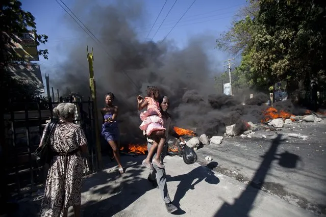 Residents run past a burning barricade set by public transportation drivers at the start a their two day strike over the cost of fuel in Port-au-Prince, Haiti, Monday, February 2, 2015. (Photo by Dieu Nalio Chery/AP Photo)