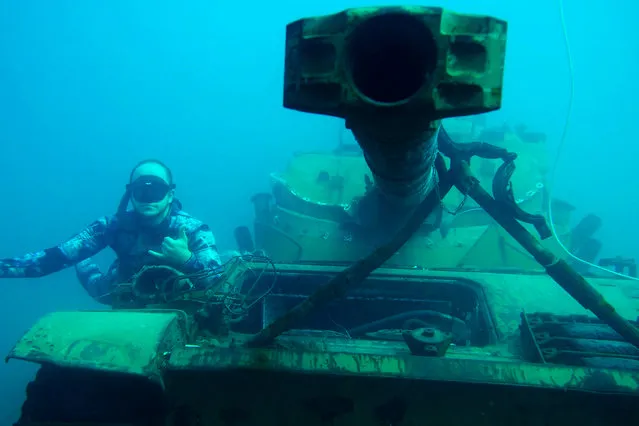 A diver poses for a photograph next to an immersed tank off the coast of the southern Lebanese port city of Sidon on August 1, 2018. Environmental activists on July 28 dropped off old battle tanks provided by the Lebanese Armed Forces into the Mediterranean Sea, about three kilometres off the coast of the southern Lebanese port city of Sidon to create new habitat for marine life. (Photo by Ibrahim Chalhoub/AFP Photo)